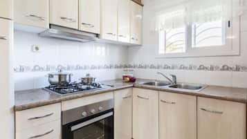 Een koelkast, een magnetron, een oven, kookgerei, borden en bestek