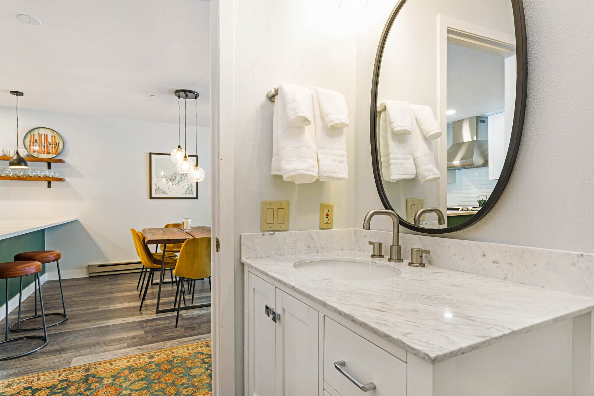 A modern bathroom with a marble sink, a large mirror, and white towels.