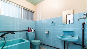 Ein Badezimmer mit blauen Fliesen, einem Waschbecken, einer Toilette und einer Badewanne.
