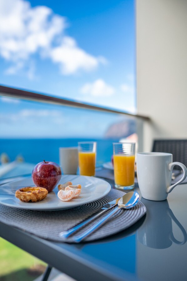 A breakfast table with a plate of food, a glass of orange juice, and a mug.