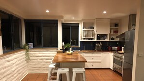 A modern kitchen with a wooden island, white cabinets, and a stainless steel refrigerator. - Lakefront@Tyrolean House Waterfront EAST JINDABYNE (East Jindabyne)