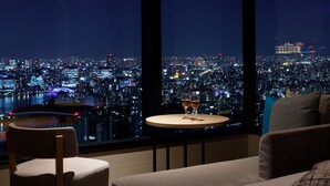 Una habitación moderna con vista a la ciudad, una mesa redonda con vasos, un sofá y una silla.