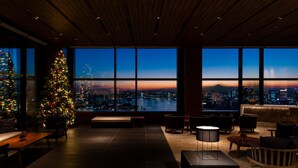 Un interior moderno con un gran árbol de Navidad, vistas a la ciudad a través de amplias ventanas y muebles contemporáneos.