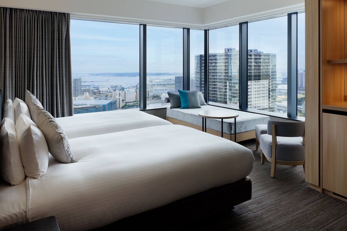 Una habitación de hotel con una cama grande, un área de estar con vistas y una mesita.