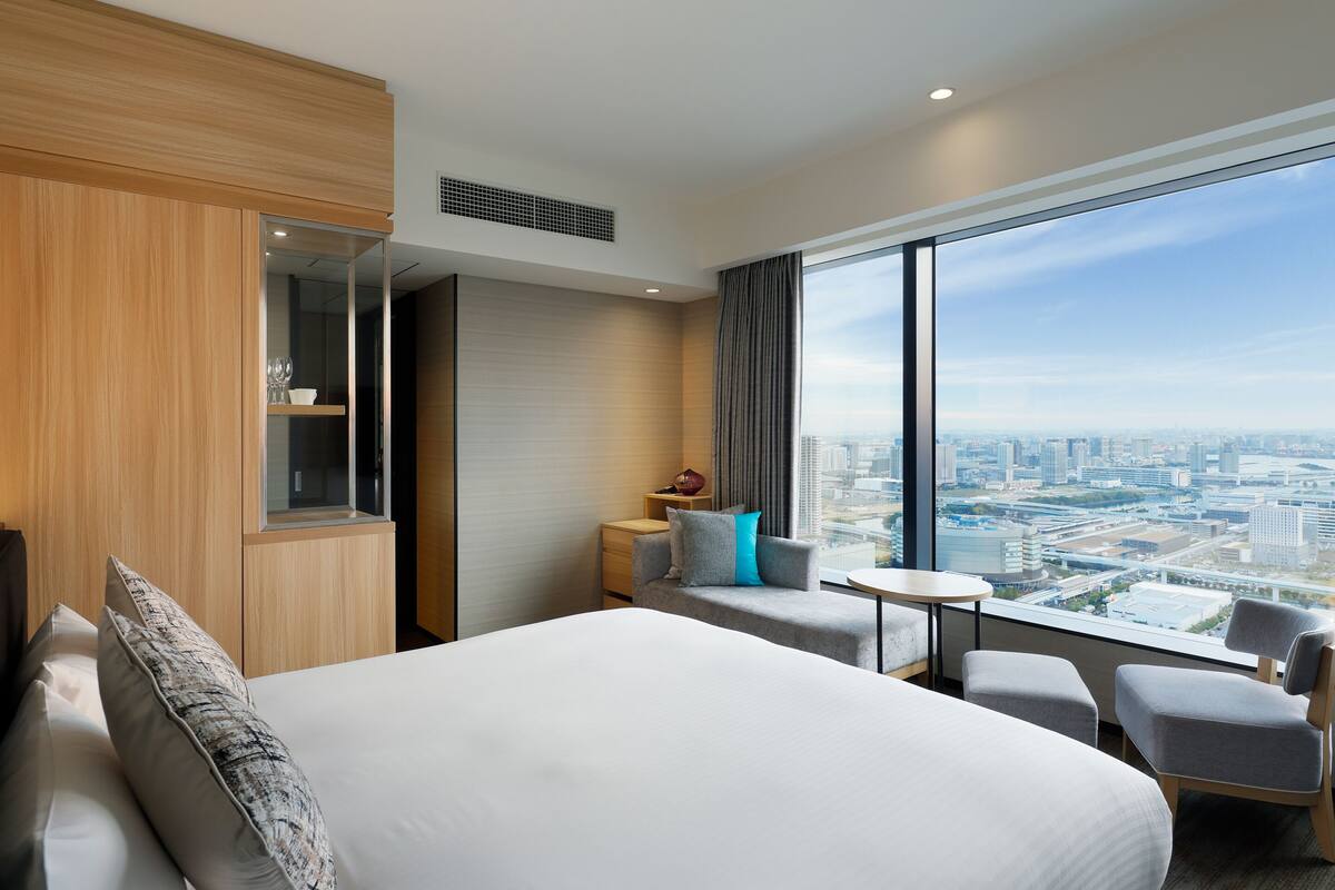 Habitación de hotel con una cama grande, una mesita, un sofá y vistas a la ciudad.