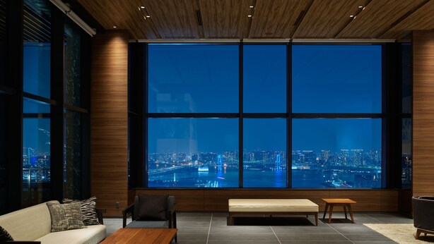 Una sala de estar moderna con un amplio ventanal que ofrece vistas a la ciudad de noche.