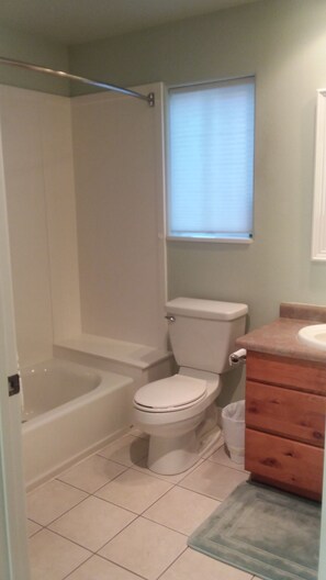 Een bad/douchecombinatie, handdoeken, toiletpapier