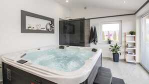 Ein modernes Badezimmer mit Whirlpool, einer gläsernen Duschkabine und einem Fenster mit Blick.