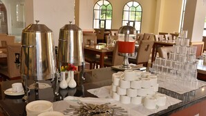 A buffet setup with multiple serving stations, including a coffee station with a coffee pot and a beverage dispenser. - Ags Holiday Resorts (Tirupattur)