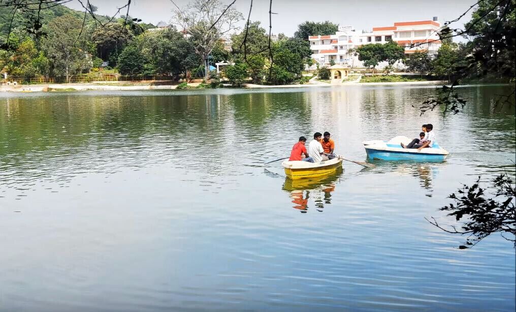 Two boats on a calm lake with buildings in the background.
