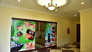 A hallway with a checkered floor, a chandelier, and mirrored walls with spa-themed artwork. - Ags Holiday Resorts (Tirupattur)