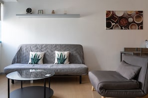 A modern living room with a grey sofa, a round glass coffee table, and a grey armchair. - Prime BGC Location Apartments by PH Staycation (Taguig)