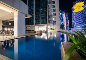 Uma área de piscina moderna de hotel, com vista clara da piscina, espreguiçadeiras e edifícios próximos.