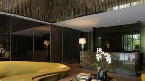 A modern lobby with a unique yellow seating area, a reception desk, and a large window providing a view of the outdoors. - KL Tower - PH Staycation (Makati)