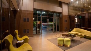 A modern lobby with yellow chairs, a glass entrance, and a wooden interior. - KL Tower - PH Staycation (Makati)