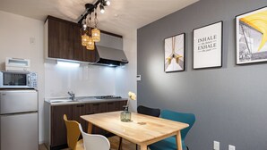 A modern kitchen with a wooden table, two chairs, a microwave, and a sink.