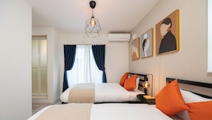 A hotel room with two beds, a nightstand with a lamp, and artwork on the wall.