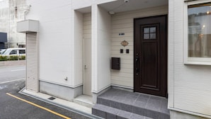 A building with a dark brown door, a small mailbox, and a security camera.