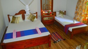 A room with two wooden beds, a mirror, a bedside table with a lamp, and a window with curtains.