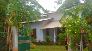 A house with a white exterior, a corrugated metal roof, and a green gate.