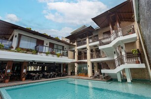 Um hotel com piscina, área de estar externa e várias varandas.