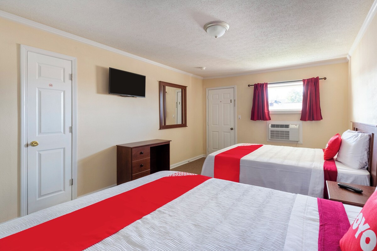 Habitación de hotel con dos camas, televisión, armario y ventana con cortinas.