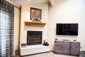 A living room with a fireplace, a mounted TV, and a patterned curtain.