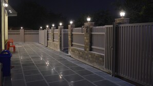 A gated outdoor area with tiled flooring and a white fence. - Ashira Inn (Greater Noida)