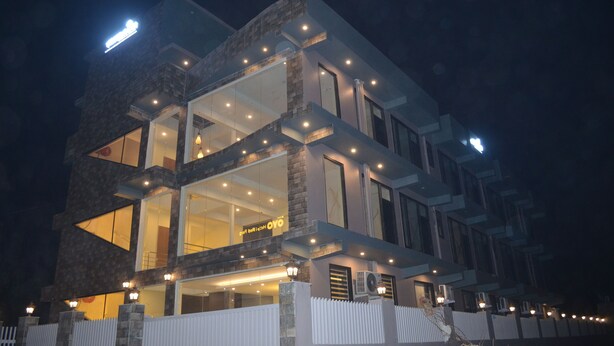 A modern multi-story building with large windows and a well-lit facade at night. - Ashira Inn (Greater Noida)