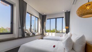 Habitación de hotel con dos camas, ventanas amplias y vista a la ciudad.
