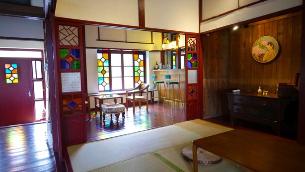 Una habitación japonesa tradicional con suelo de tatami, una mesa de madera baja y una zona de bar con taburetes.