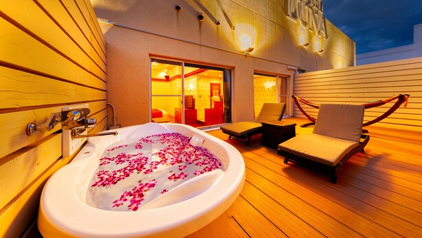 A hot tub with rose petals, a lounge chair, and a view of the hotel's interior. - Hotel Luna Otsu (Otsu)