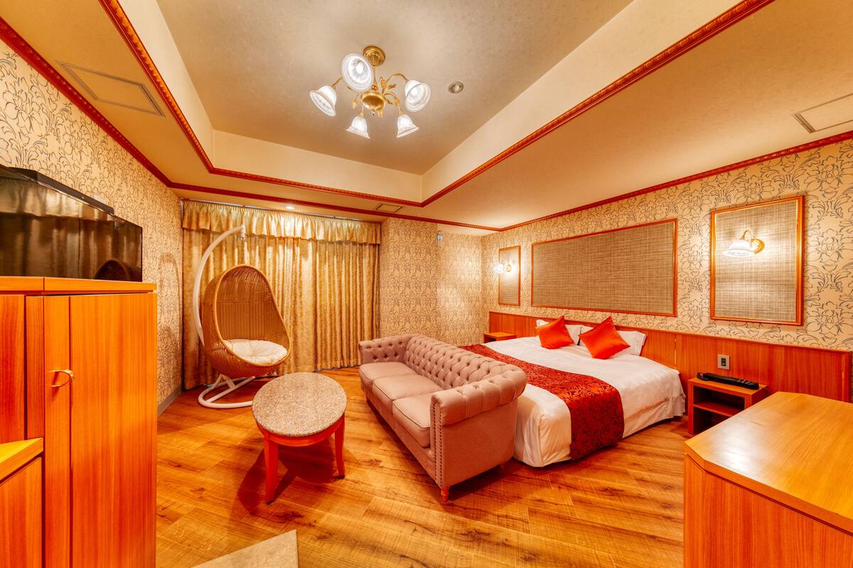 A hotel room with a large bed, a sofa, a round table, and a wardrobe.