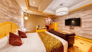 A hotel room with a large bed, a leather sofa, a flat-screen TV, and a minibar. - Hotel Luna Otsu (Otsu)