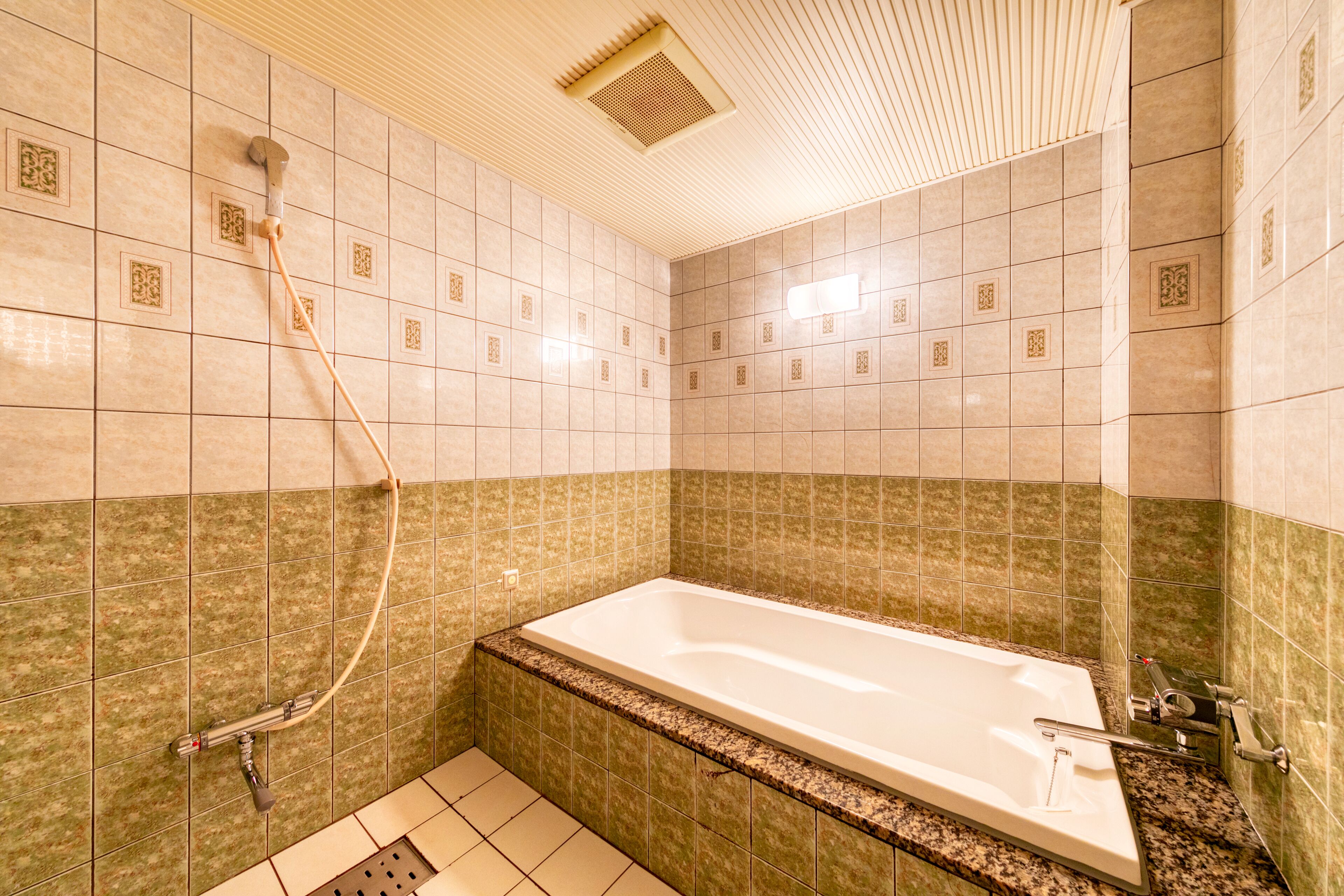 A bathroom with a bathtub, shower, and tiled walls.