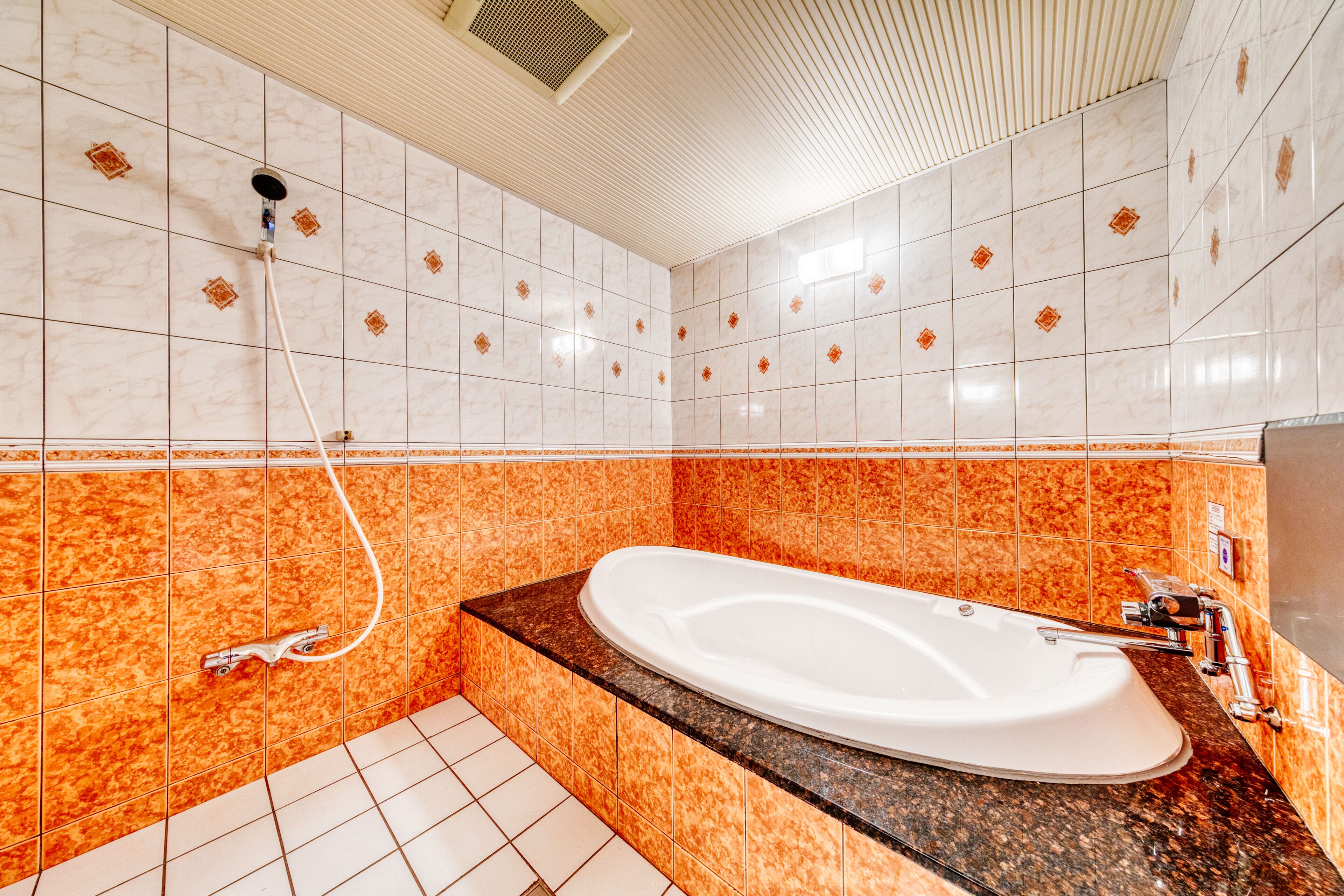 A bathroom with a large bathtub, tiled walls, and a shower head.