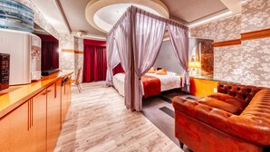A hotel room with a canopy bed, a sofa, a minibar, and a bathroom with a shower and toilet. - Hotel Luna Otsu (Otsu)