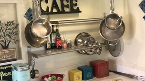 Et køkken med en stålløber, kaffemaskine og mærkede beholdere til te, sukker og mel.