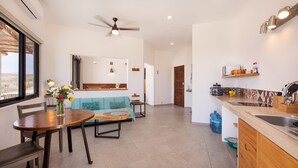 A modern kitchen with a dining area, including a wooden table, chairs, and a sofa. - CASA TAKO 2, CLEAN modern studio unit, 5 minutes walk to kite launch beach. (La Ventana)