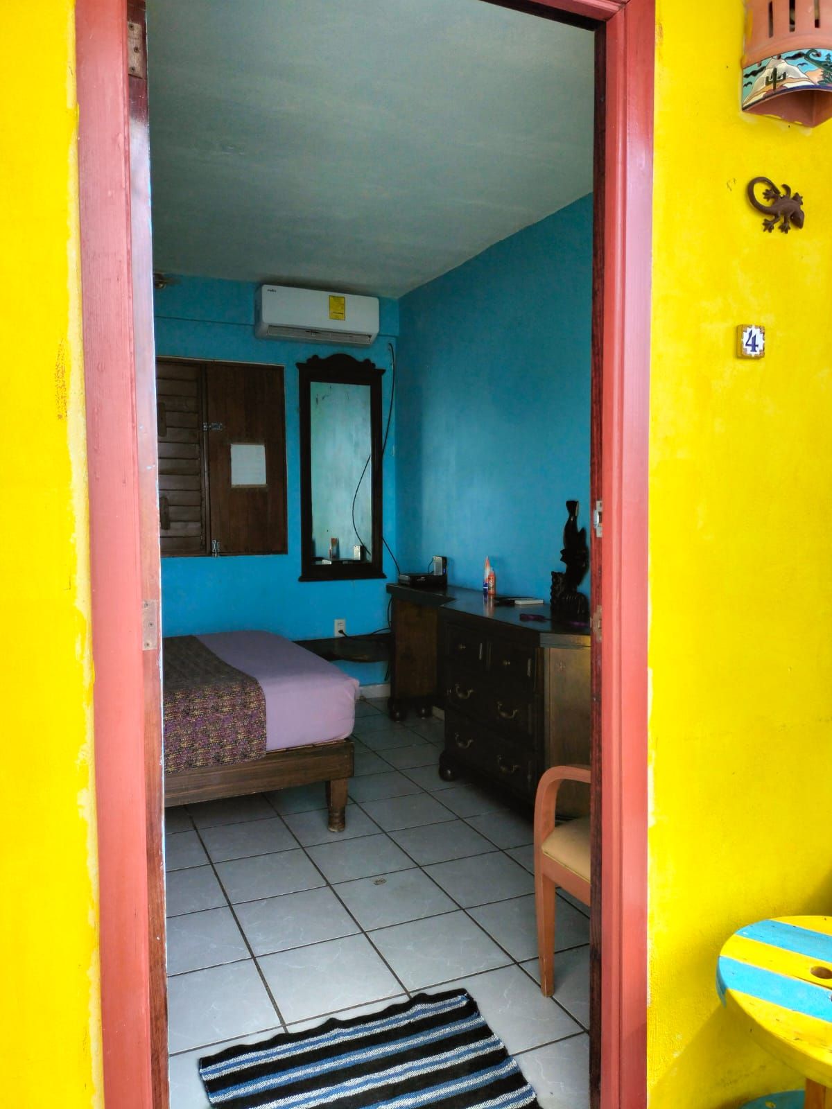 Een kamer met een bed, een dressoir, een spiegel en een raam.
