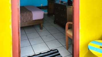 Een kamer met een bed, een dressoir, een spiegel en een raam.