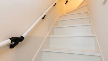 A staircase with white steps and handrails, leading to a landing with a light fixture.