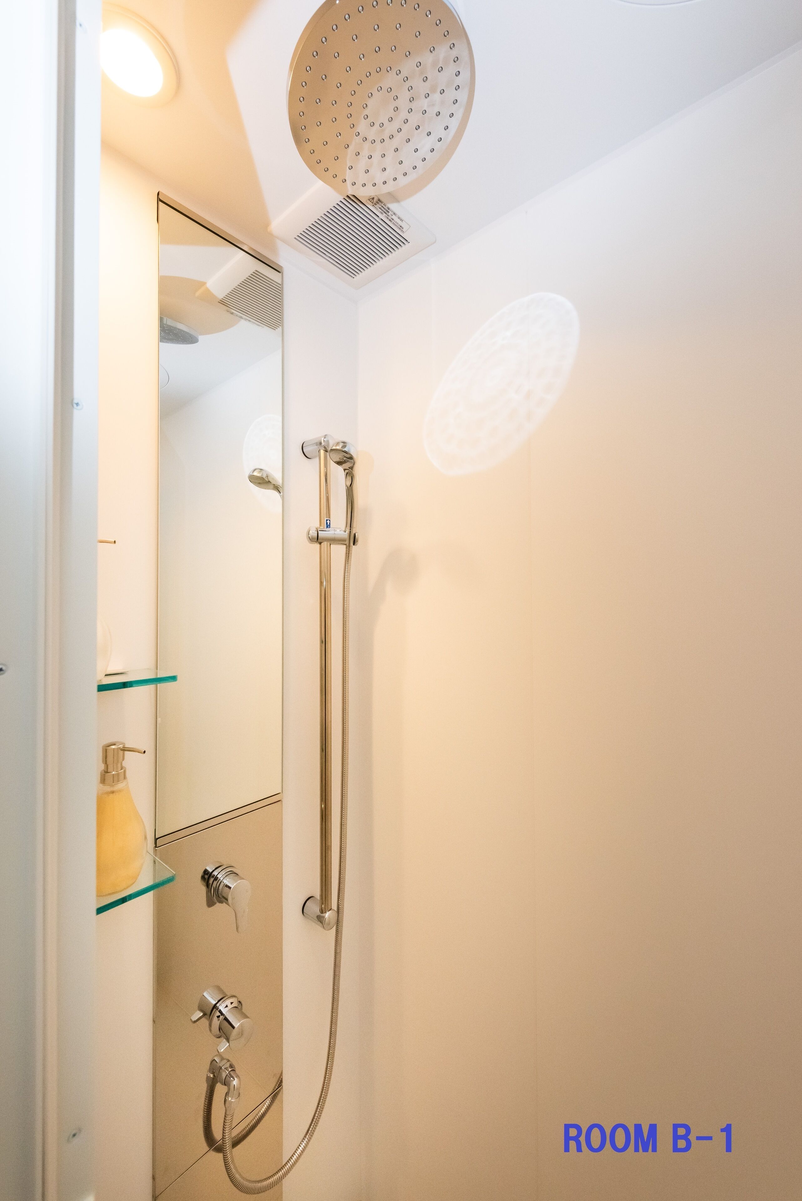 Un baño moderno con ducha, estante de vidrio y espejo.