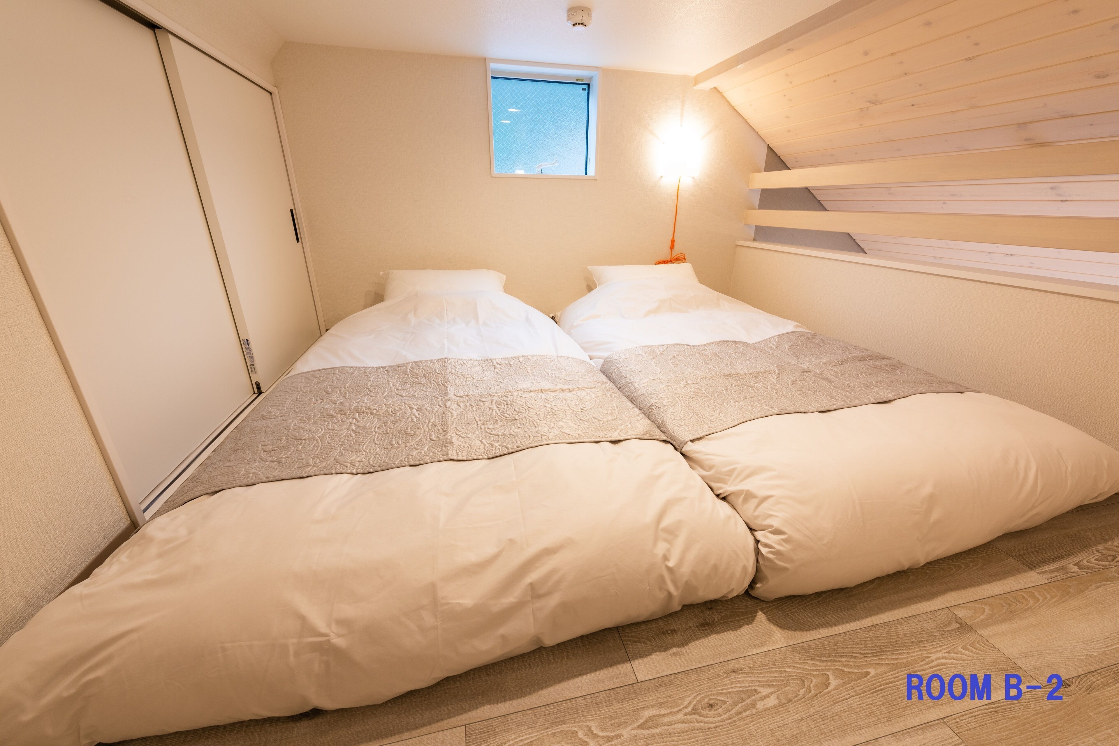Ein Schlafzimmer mit einem Bett, einem Fenster und einer Wand aus Holzlatten.