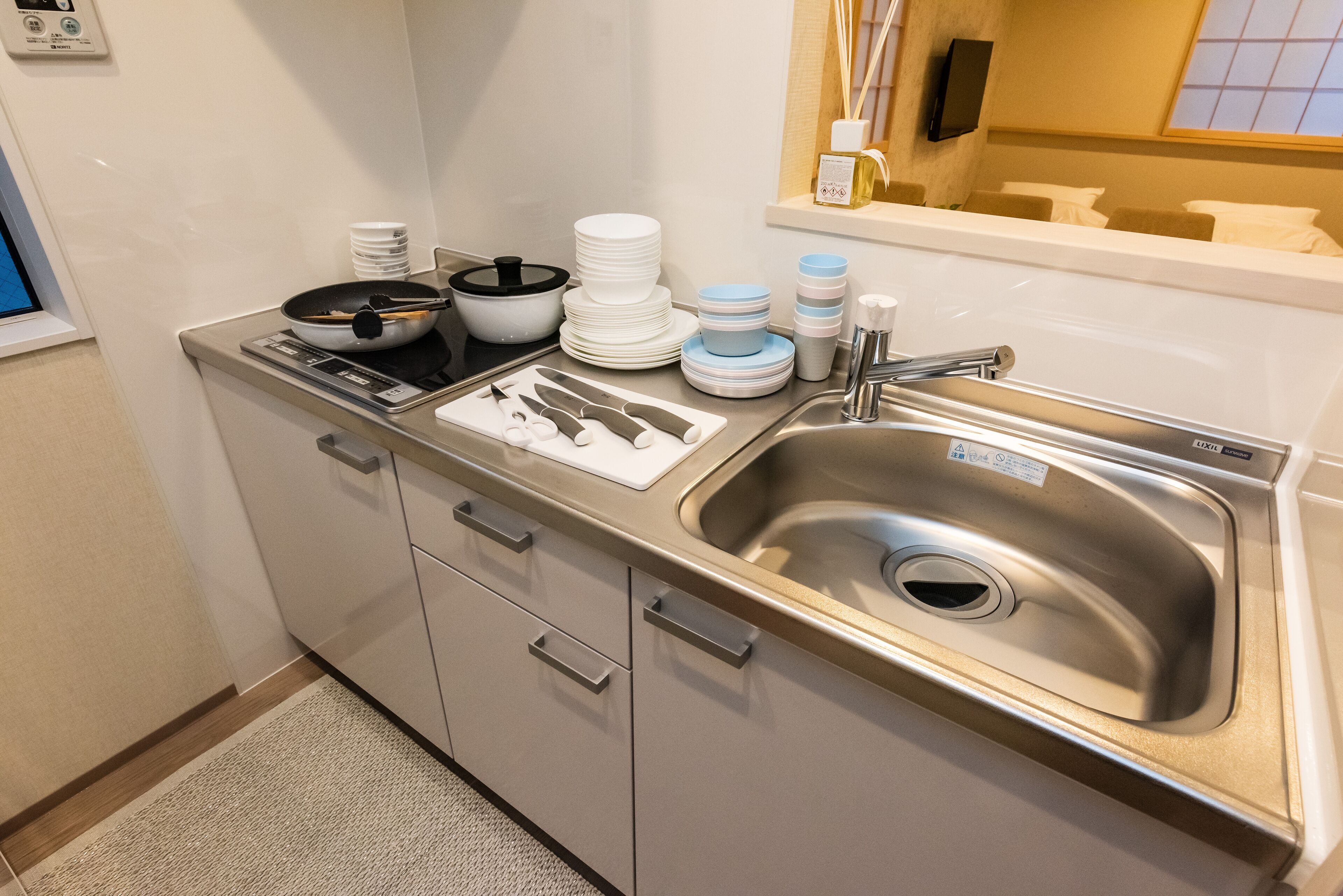 A modern kitchen with stainless steel appliances, a sink, and neatly stacked dishes.