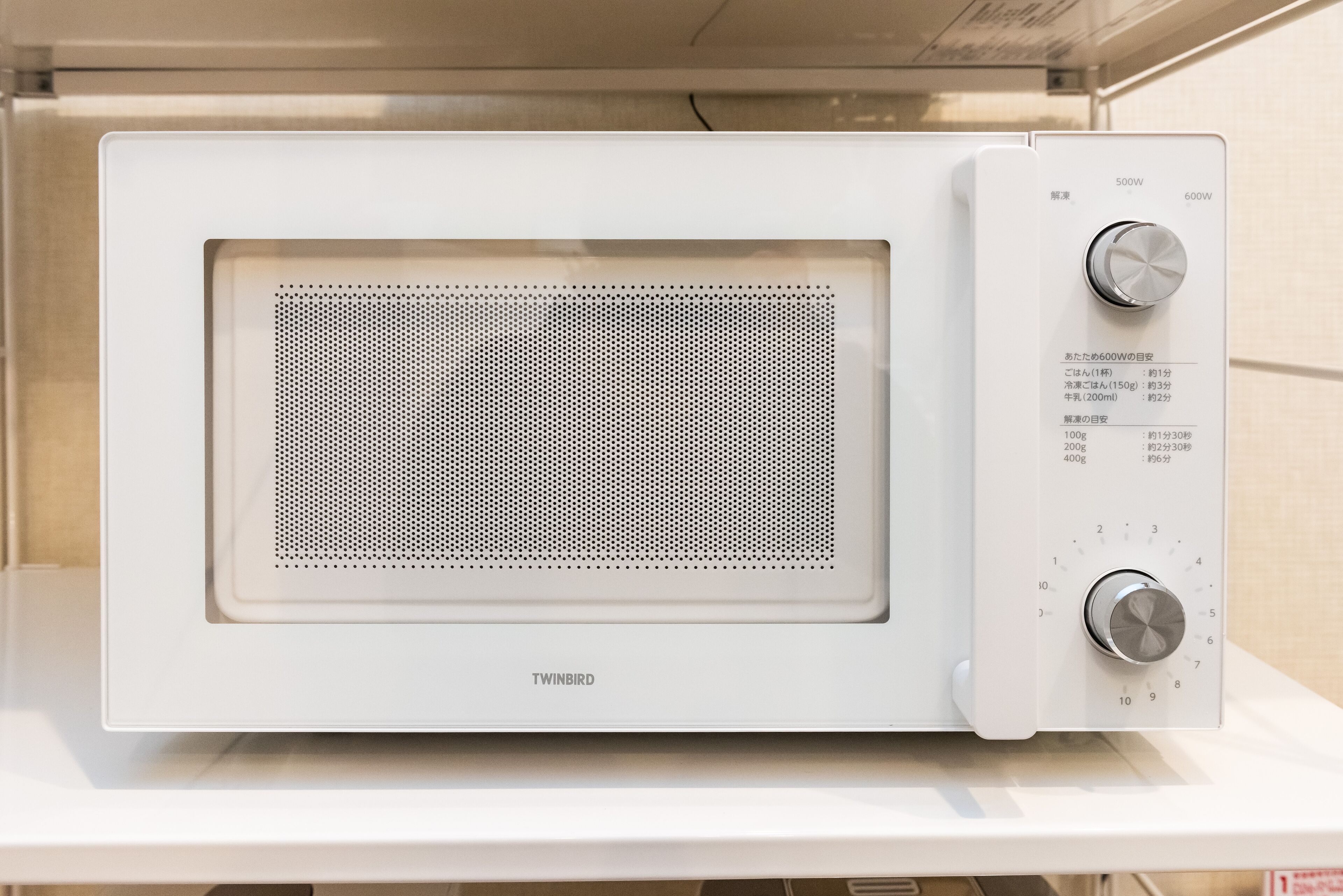 A white Twinbird microwave oven with a control panel featuring power settings and a timer.