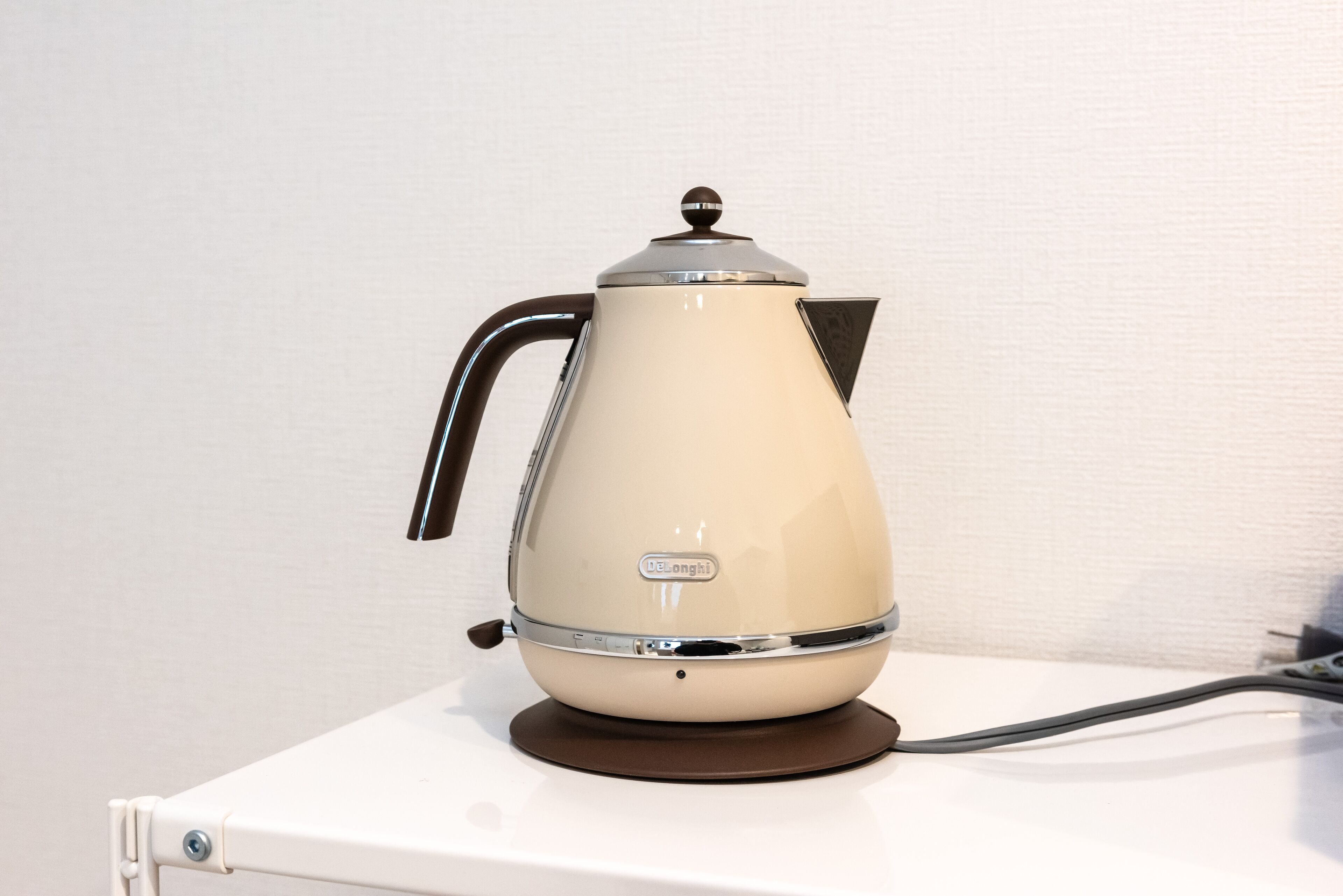 A vintage-style electric kettle with a handle and a spout, placed on a white surface.