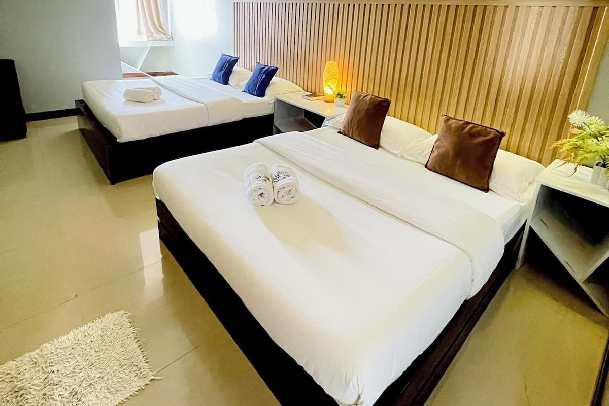 A modern hotel room with two beds, a bedside table with a lamp, and a large window.