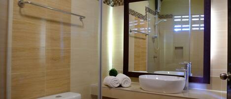 A bathroom with a toilet, a sink, a shower, and a mirror.