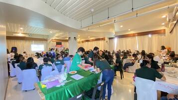 Una sala de conferencias con mesas redondas, sillas blancas y mantel verde.